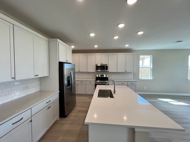 kitchen with stainless steel appliances, dark hardwood / wood-style flooring, a kitchen island with sink, and sink