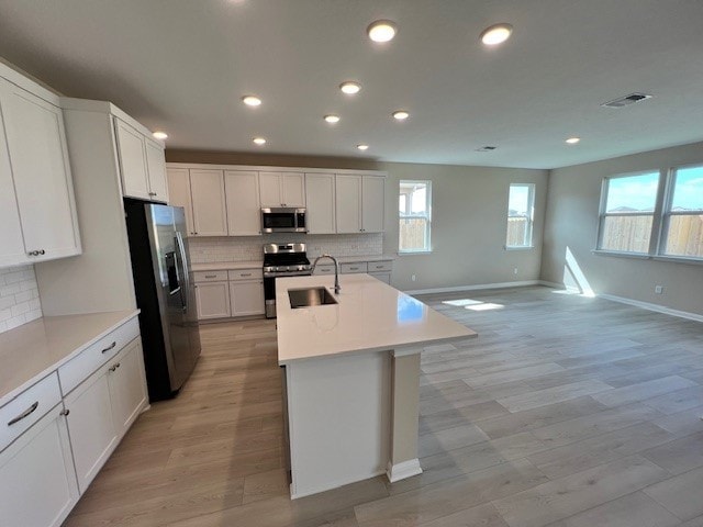 kitchen featuring appliances with stainless steel finishes, sink, white cabinets, and light hardwood / wood-style floors