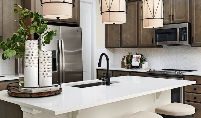 kitchen featuring stainless steel appliances, a kitchen breakfast bar, sink, and tasteful backsplash