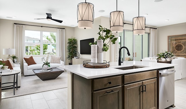 kitchen featuring decorative light fixtures, sink, ceiling fan, a center island with sink, and dark brown cabinetry