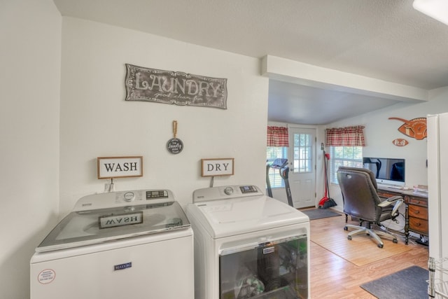 laundry area with independent washer and dryer, light wood-type flooring, and a textured ceiling