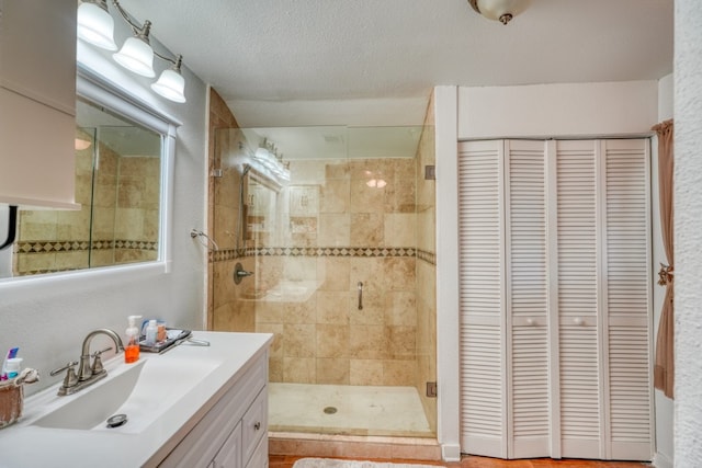 bathroom featuring a textured ceiling, vanity, and a shower with door