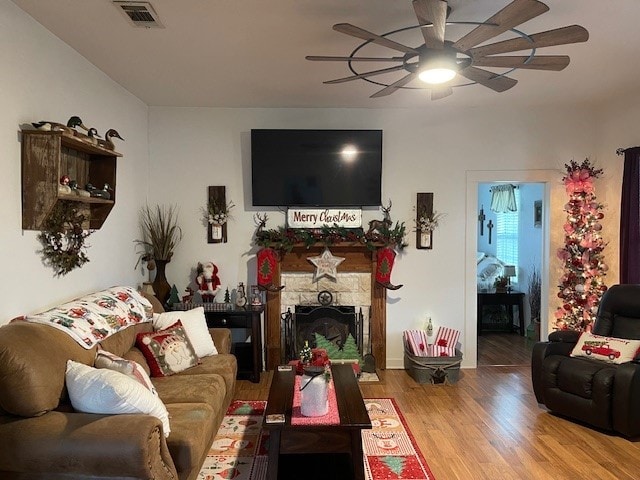 living room featuring a stone fireplace and hardwood / wood-style flooring