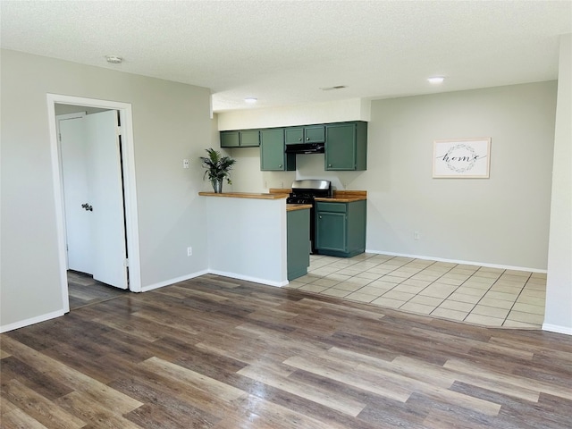 kitchen featuring a textured ceiling, light hardwood / wood-style flooring, and green cabinetry