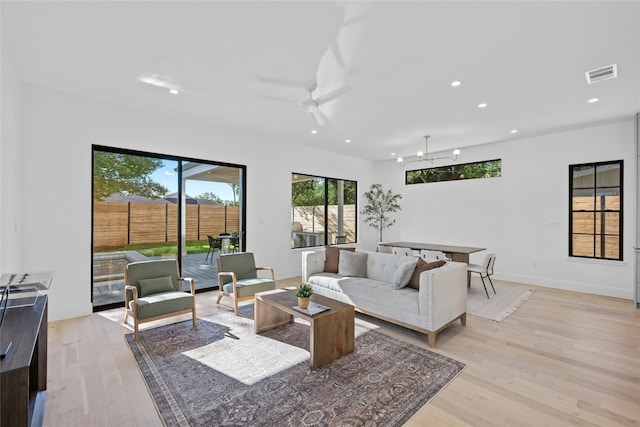 living room featuring light hardwood / wood-style floors and ceiling fan with notable chandelier