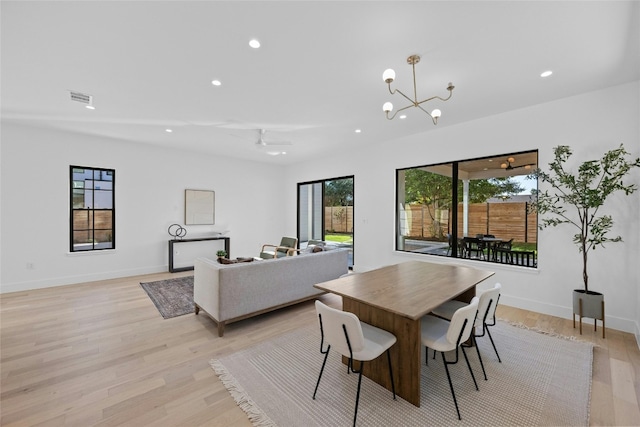 dining area with light hardwood / wood-style flooring and ceiling fan with notable chandelier