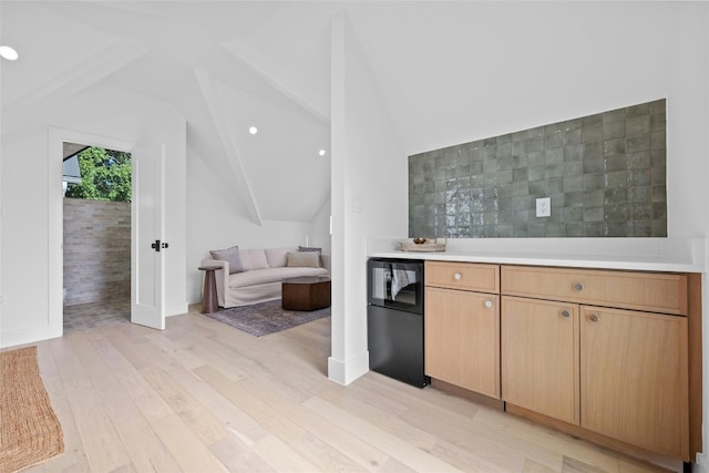 kitchen featuring black fridge, lofted ceiling, and light hardwood / wood-style flooring