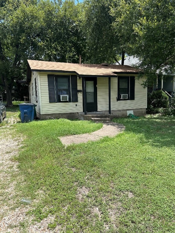 single story home with cooling unit and a front yard