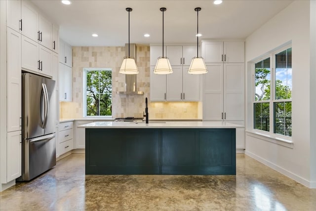 kitchen featuring white cabinets, pendant lighting, an island with sink, and stainless steel fridge