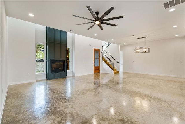 unfurnished living room with concrete flooring and ceiling fan with notable chandelier