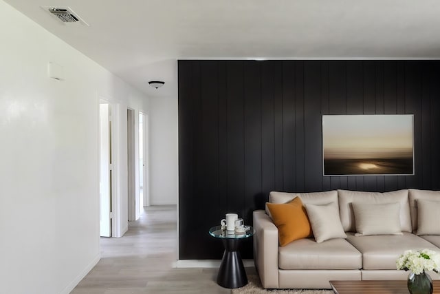 living room featuring light hardwood / wood-style flooring and wood walls