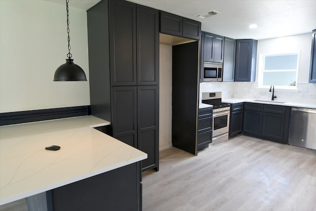 kitchen featuring pendant lighting, kitchen peninsula, stainless steel appliances, and sink