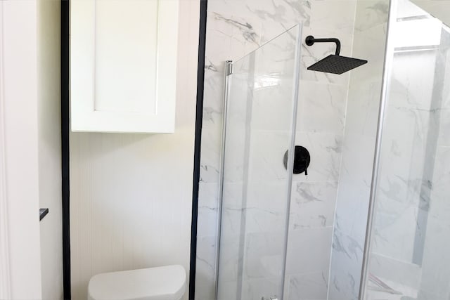 bathroom featuring toilet and a shower with shower door