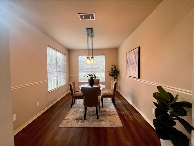 dining area with dark wood finished floors, visible vents, and baseboards