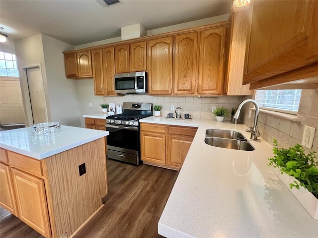 kitchen featuring a center island, sink, dark hardwood / wood-style floors, appliances with stainless steel finishes, and tasteful backsplash