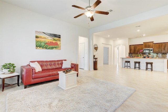 living room with visible vents, a ceiling fan, recessed lighting, arched walkways, and light tile patterned floors