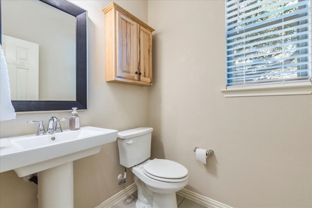 bathroom with baseboards, a sink, toilet, and tile patterned floors