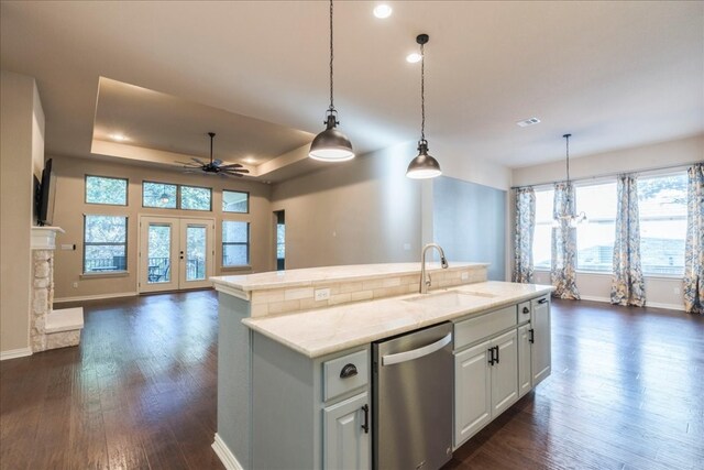 kitchen with a tray ceiling, french doors, open floor plan, a sink, and dishwasher