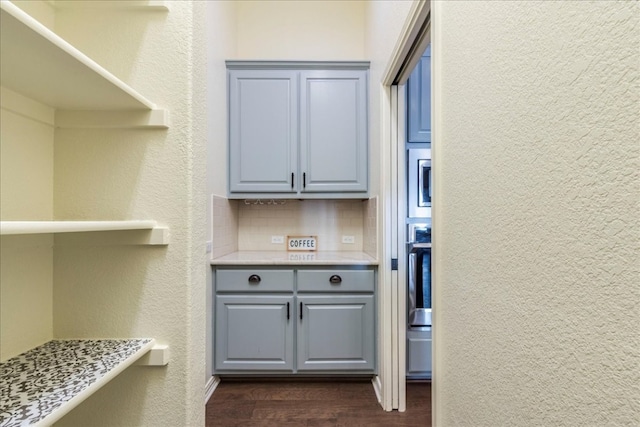 interior space featuring oven, tasteful backsplash, dark wood finished floors, and a textured wall