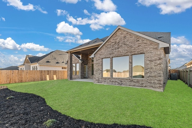 back of property with a yard, a patio area, and central AC