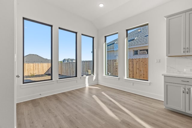 unfurnished dining area with lofted ceiling and light wood-type flooring