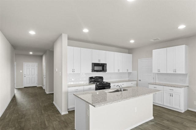 kitchen with a kitchen island with sink, white cabinets, a sink, light stone countertops, and black appliances