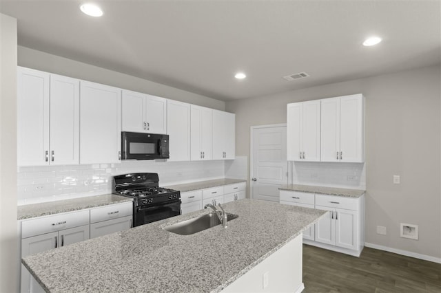 kitchen featuring a center island with sink, white cabinets, a sink, and black appliances