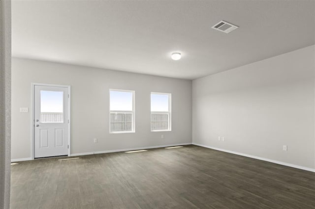 spare room featuring visible vents, dark wood finished floors, and baseboards