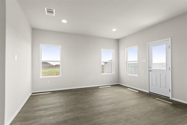 empty room featuring baseboards, plenty of natural light, visible vents, and dark wood-type flooring