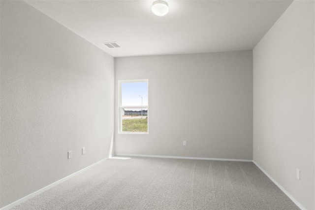 carpeted spare room with visible vents and baseboards