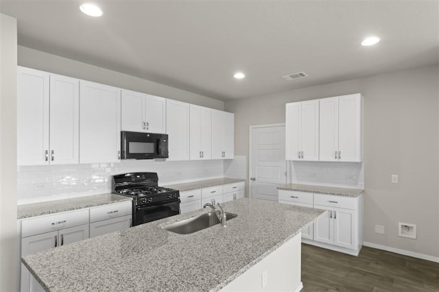 kitchen with visible vents, dark wood-type flooring, a sink, an island with sink, and black appliances