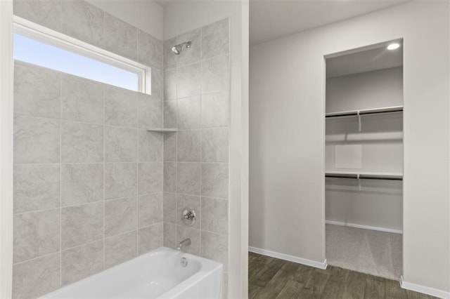 full bath featuring bathtub / shower combination, wood finished floors, a walk in closet, and baseboards