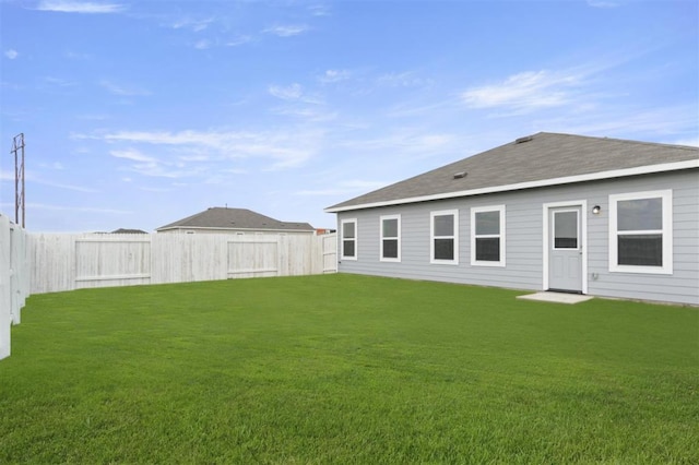 rear view of property with a fenced backyard, a lawn, and roof with shingles