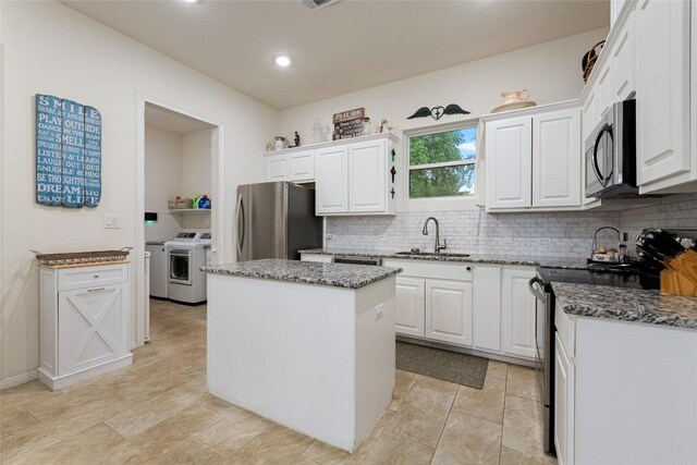 kitchen with white cabinets, stainless steel appliances, sink, separate washer and dryer, and a kitchen island