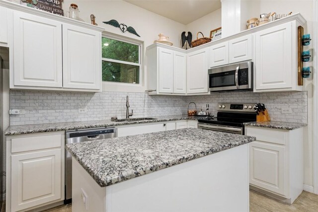 kitchen featuring white cabinetry, a kitchen island, stainless steel appliances, and light stone countertops