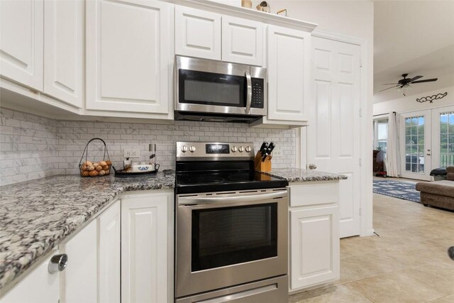 kitchen with light stone countertops, french doors, stainless steel appliances, ceiling fan, and white cabinets