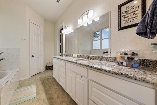 bathroom with vanity and tiled bath