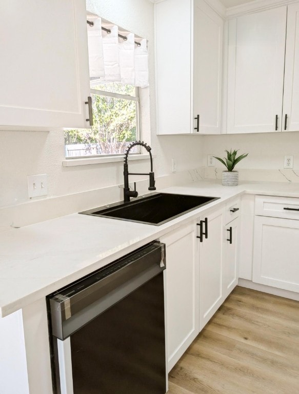 kitchen with white cabinets, black dishwasher, light hardwood / wood-style flooring, and sink