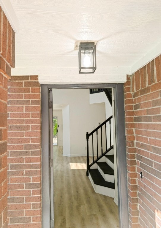 interior space featuring wood-type flooring and brick wall