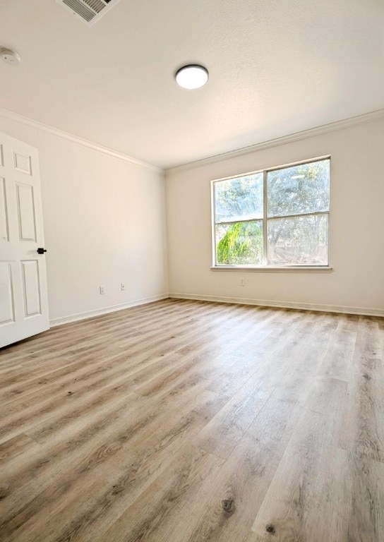 empty room featuring light wood-type flooring and ornamental molding