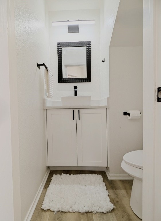 bathroom with hardwood / wood-style flooring, vanity, and toilet