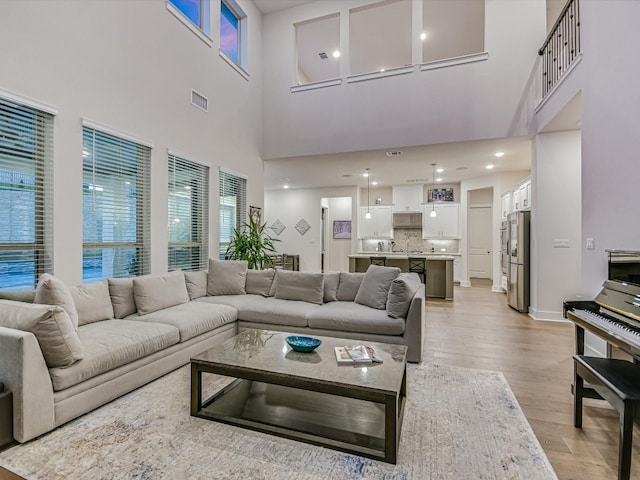 living room with light hardwood / wood-style flooring and a towering ceiling