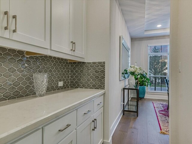 kitchen with light stone countertops, tasteful backsplash, dark hardwood / wood-style flooring, and white cabinetry