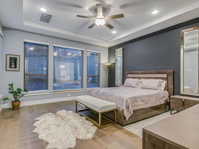 bedroom featuring hardwood / wood-style floors, ceiling fan, and a raised ceiling