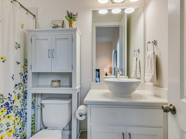 bathroom with curtained shower, toilet, and vanity