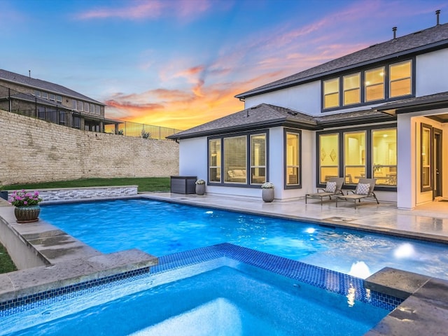 pool at dusk with a patio area