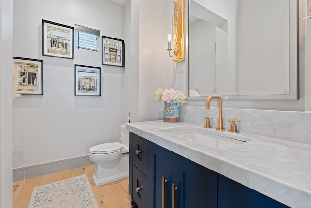 bathroom with hardwood / wood-style flooring, toilet, and vanity