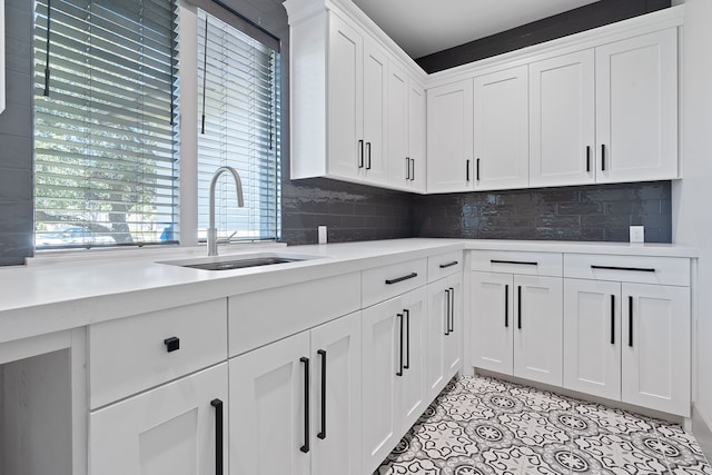 kitchen with decorative backsplash, sink, white cabinets, and light tile patterned floors