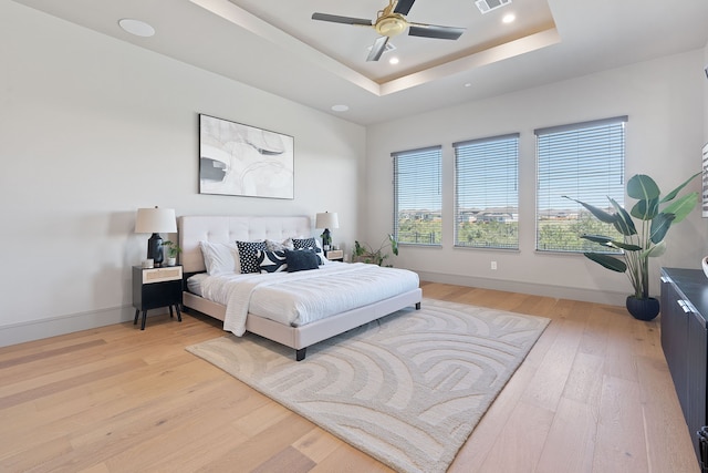 bedroom featuring wood-type flooring, ceiling fan, and a raised ceiling