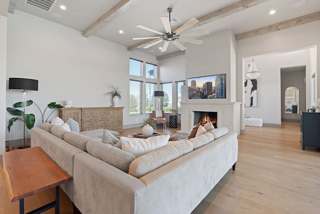 living room featuring light wood-type flooring, beam ceiling, and ceiling fan